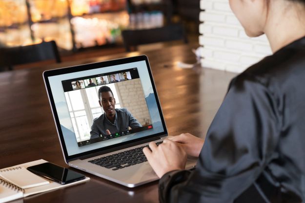 A person conducting a Zoom call on a laptop while sat at a desk.