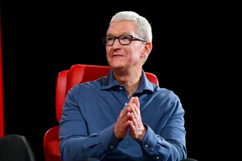 Tim Cook sitting on a red chair in front of a black background with his hand held together